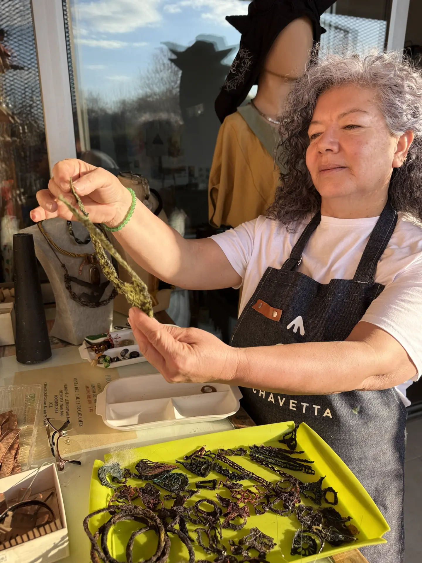 María Teresa Chavetta examinando una pieza fibrosa entre sus manos en el taller.