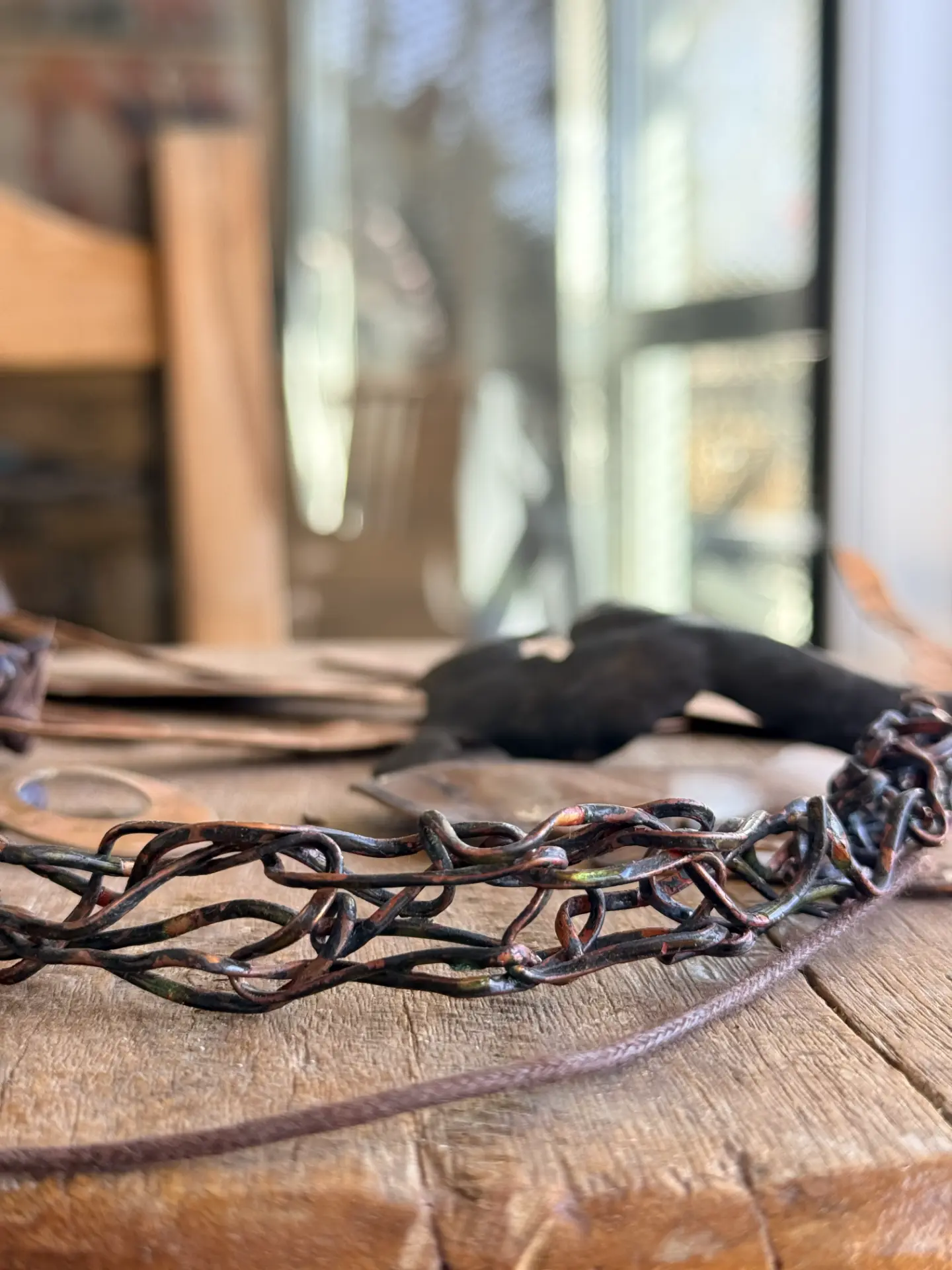 Cadena de eslabones de cobre sobre la mesa de trabajo del taller.